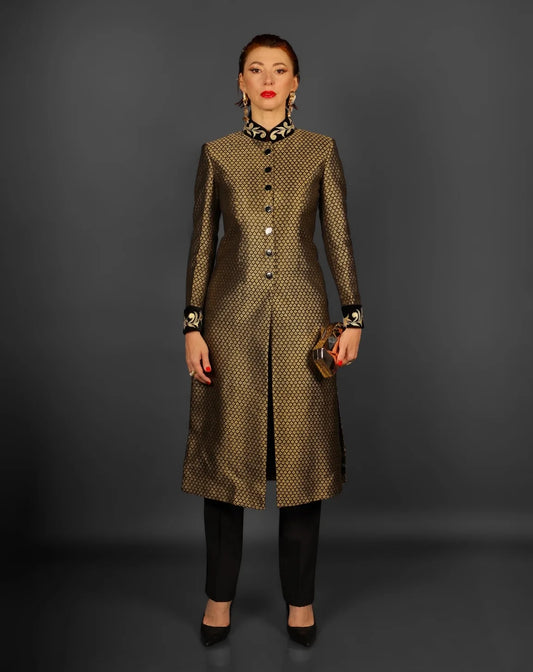 A woman wearing a knee-length gold and black brocade sherwani jacket with a front slit.